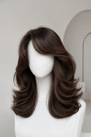 A medium-length brown wig with soft waves and a straight fringe, displayed on a white mannequin head against a light gray background, Obroi