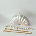 Shell-shaped handbag with a beaded strap on a light gray background, Obroi