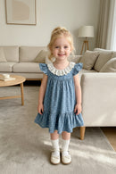 Young girl in a blue dress standing in a living room, Obroi