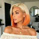 A woman with a short blonde bob haircut featuring vibrant orange ombre ends, wearing a cream off-the-shoulder top and a small gold pendant necklace in a modern living room setting, Obroi