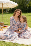 Woman and young girl in matching polka dot dresses sitting on a picnic blanket in a park, Obroi