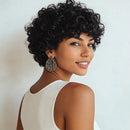 Woman with short, curly black hair wearing a white top against a light background, Obroi