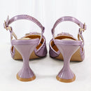 A pair of women's high-heeled sandals shown from the back, featuring a glossy lavender-purple heel and straps embellished with rhinestones, set against a plain white background, Obroi