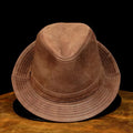 Brown suede hat on a wooden surface with a black background, Obroi