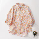 Floral patterned shirt on a white surface with a small plant in the corner, Obroi