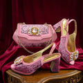 Pink high-heeled shoes and matching handbag with decorative elements on a red fabric background, Obroi