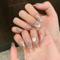 Hand with decorative nails featuring pearls and crystals on a blurred background, Obroi