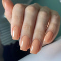 Hand with peach-colored nails on a blurred background, Obroi