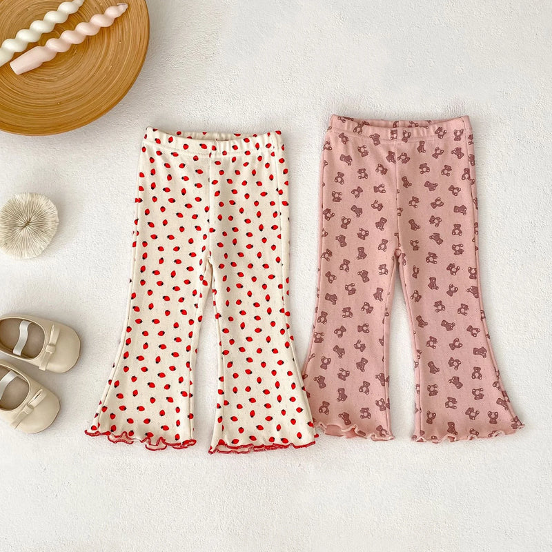 Two pairs of patterned pants on a light surface with baby shoes nearby, Obroi