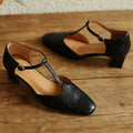 Black leather shoes with T-straps on a wooden floor, Obroi