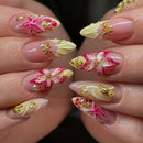 Nails with pink, yellow, and gold floral designs on a blurred background, Obroi
