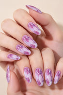 A close-up of hands with long almond-shaped nails decorated in a pink and white marble pattern, set against a soft beige background, Obroi