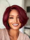 Woman with burgundy hair smiling in a blurred indoor setting, Obroi