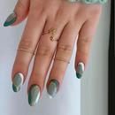 Hand with green and gold nail design and gold rings on a white background, Obroi