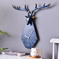 Decorative wall clock shaped like a deer head with antlers on a gray wall, Obroi