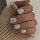 Close-up of a hand with glittery silver nail polish wearing a beige knitted sleeve, Obroi