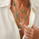 Necklace with pearls and turquoise beads worn by a person in a white shirt, Obroi