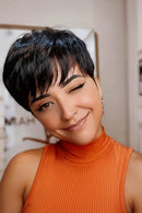 Woman with a stylish haircut wearing an orange top, smiling, Obroi