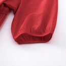 A close-up of a red garment sleeve with gathered fabric and a gathered cuff, shown on a plain white background, Obroi