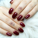 Close-up of hands with dark red nail polish on a white fur background, Obroi