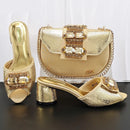 Gold high-heeled shoes and matching handbag with embellishments on a dark surface, Obroi