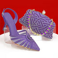 Purple high-heeled shoe and matching handbag with rhinestone details on a red background, Obroi