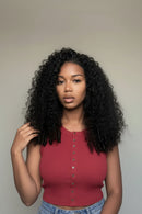 A woman with voluminous, glossy black curly hair extensions wearing a sleeveless red top, shown against a neutral indoor wall. Three inset images on the right show close-ups of the hair extension parts, strands, and attachment details, Obroi