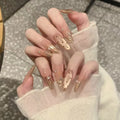 Hand with transparent nail polish and gold accents on a neutral background, Obroi