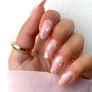 Hand with pink nails featuring white bunny designs on a light pink background, Obroi