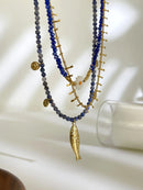 Two layered necklaces with blue beads and gold accents on a white surface, Obroi
