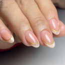 Close-up of a hand with pink nails and gold accents on a neutral background