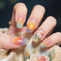 Nails with sunset gradient design held by a hand, Obroi