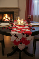 Dining table set for a romantic dinner with heart-shaped decorations, candles, and wine glasses in front of a fireplace, Obroi