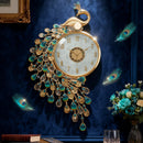 An ornate wall clock shaped like a peacock, with a gold-tone body, turquoise and teal teardrop accents, and a white clock face, shown hanging against a dark blue wall with decorative feathers, books, and a glass of whiskey nearby, Obroi