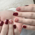 Close-up of hands with red nail polish and heart designs on a soft white background, Obroi