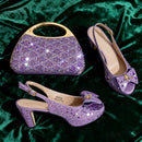 Purple embellished handbag and high-heeled shoes on a green fabric background, Obroi