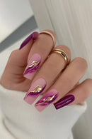 Hand with pink and purple nails featuring gold leaf designs, wearing multiple rings, Obroi