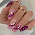 Hand with pink and purple nails featuring gold leaf designs, wearing multiple rings, Obroi
