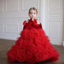 Young girl wearing a red floral dress against a white wall, Obroi