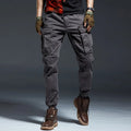 Person wearing gray cargo pants with brown boots on a dark background, Obroi
