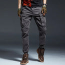 Person wearing gray cargo pants with brown boots on a dark background, Obroi