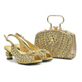 A gold embellished evening shoe and matching clutch handbag set, photographed on a clean white background. The set includes a pair of open-toe slingback heels with a chunky gold block heel and a structured rectangular clutch with a top handle, Obroi