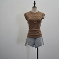 A brown short-sleeve t-shirt with small black polka dots displayed on a mannequin torso, paired with light-wash denim shorts against a plain light gray background, Obroi