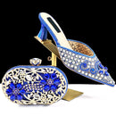 Decorative blue shoe and matching clutch with 'Obroi' branding on a black background
