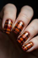 Nails with plaid design in orange, brown, and black on a dark background, Obroi
