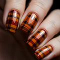 Nails with plaid design in orange, brown, and black on a dark background, Obroi