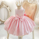 Pink dress with a large bow on a mannequin against a decorative chair and mirror background, Obroi