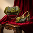 Green handbag and shoe with gemstone details on a red fabric background, Obroi