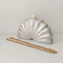 Shell-shaped clutch with a gold chain on a light gray background, Obroi