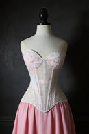 White corset with pink floral pattern on a mannequin against a dark background, Obroi